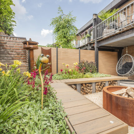 Terrassengestaltung mit Feuerschale in einem Garten mit farbenfroher Bepflanzung.