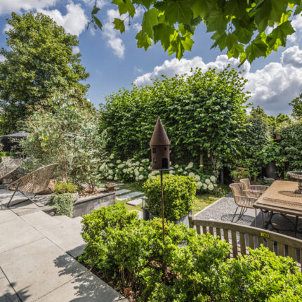 Blick auf den stilvoll angelegten Garten mit Terrassenbereich und üppiger Begrünung.