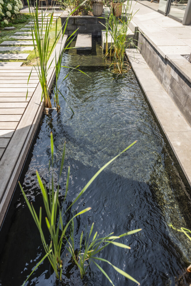 Gartenweg mit Teich und Trittplatten entlang eines Wasserelements.