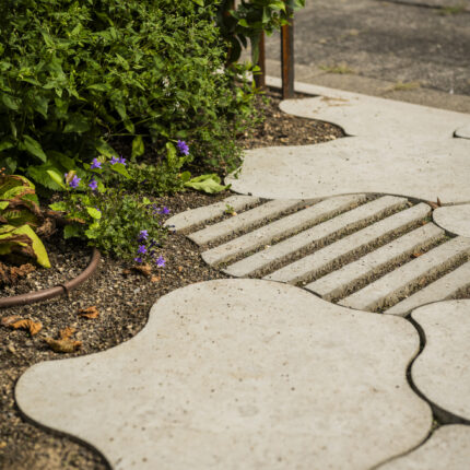 Organisch geformte Betonplatten mit Rillenstruktur als Gartenweg
