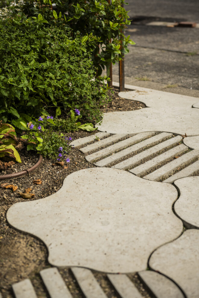 Organisch geformte Betonplatten mit Rillenstruktur als Gartenweg