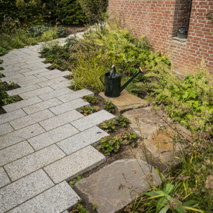 Weg aus Granitpflaster und Natursteinplatten entlang der Klinkerfassade