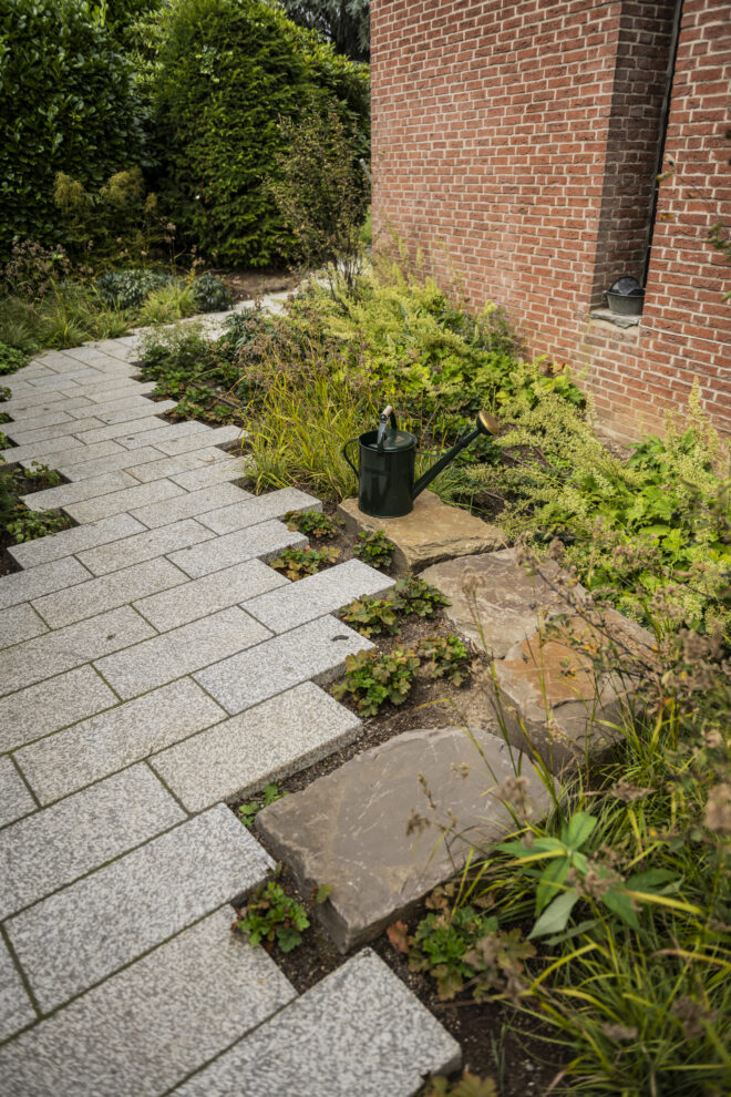 Weg aus Granitpflaster und Natursteinplatten entlang der Klinkerfassade
